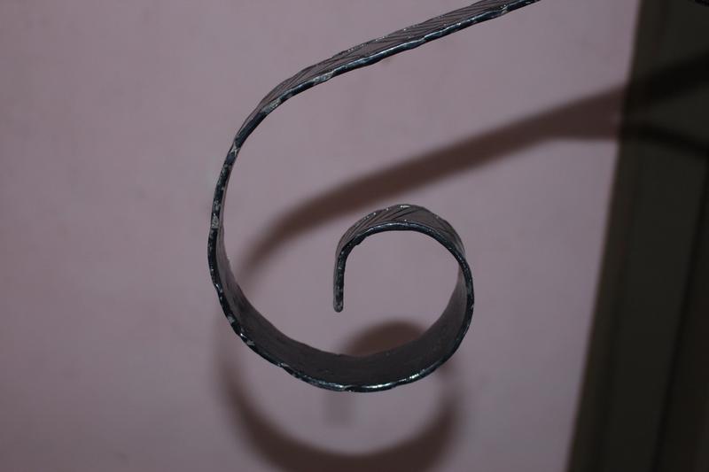 Close up of hand-forged iron scroll detail on One Step Rail product